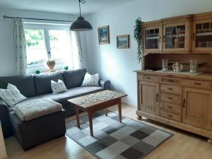 ein Wohnzimmer mit einem blauen Sofa und einem Tisch in der Unterkunft FeWo Hansl`s Freiraum - Berchtesgaden - Schönau am Königssee in Schönau am Königssee