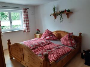 Schlafzimmer mit einem Holzbett mit roten und weißen Kissen in der Unterkunft FeWo Hansl`s Freiraum - Berchtesgaden - Schönau am Königssee in Schönau am Königssee