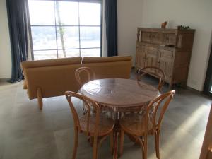 uma sala de estar com um sofá, uma mesa e cadeiras em l'abri'gîte sous les arbres em Huy