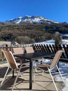 a table and chairs on a roof with a snow covered mountain at Montclar Appart 4 à 6 places - terrasse vue panoramique - idéalement situé in Montclar