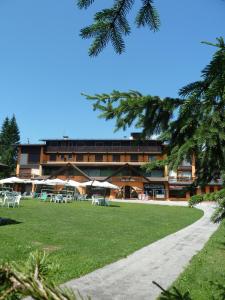 a large building with tables and chairs in a park at Albergo Miramonti Dependance in Asiago