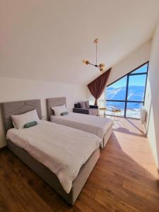 two beds in a room with a large window at Gudauri Travel Chalets in New Gudauri in Gudauri