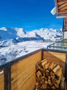 a pile of wood on a balcony with snow covered mountains at Gudauri Travel Chalets in New Gudauri in Gudauri