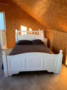 1 cama blanca en un dormitorio con techo de madera en La maison du poulailler en Jargeau