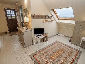 a living room with a tv and a rug at The Loft Room in Dymock