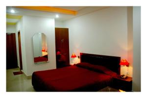 Schlafzimmer mit einem roten Bett und einem Spiegel in der Unterkunft Hotel Dooars Mountain in Alīpur Duār