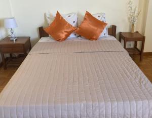 a bed with orange and white pillows on it at Pendora Appartements in Mindelo