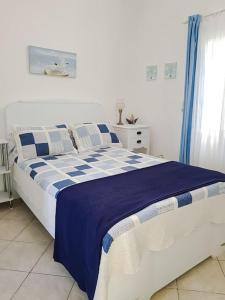 een slaapkamer met een bed met blauwe en witte lakens bij Blue4u in Imerovígli