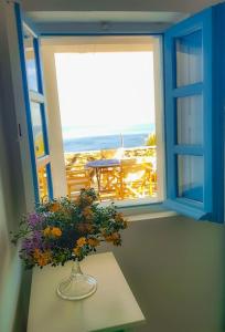 a vase with flowers on a table in front of a window at Blue4u in Imerovigli