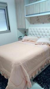 a bedroom with a white bed with pink sheets and a window at Apartamento aconchegante em Bento Gonçalves, próximo ao vale dos vinhedos in Bento Gonçalves