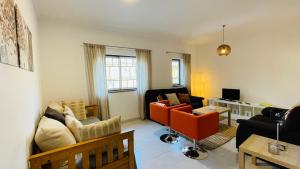 ein Wohnzimmer mit orangefarbenen Stühlen und einem Sofa in der Unterkunft Bicos 101 by Check-in Portugal in Albufeira