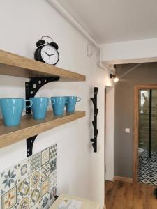 a shelf with blue cups and a clock on a wall at Perfect Stay Apartment Petrosani in Petroşani