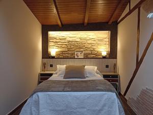 sypialnia z łóżkiem i kamienną ścianą w obiekcie El Cascanueces - Casa Rural w mieście Candelario
