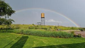 a rainbow over a garden with a water tower at Forest Hill Country Lodge in Piet Retief