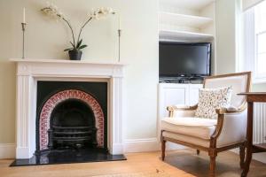 a living room with a fireplace and a chair at Stunning Chelsea Nest in London