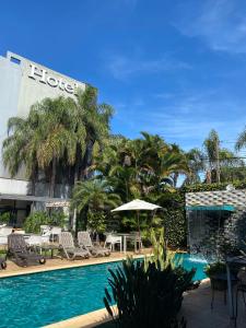 una piscina en un hotel con sillas y sombrillas en Milord Hotel en Encarnación