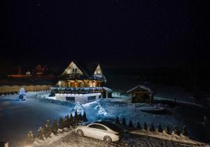 um carro estacionado em frente a uma casa na neve em Domek w górach DeLuxe sauna,jacuzzi,basen,hot tub-Nowy Targ blisko Białka ,Zakopane em Nowy Targ