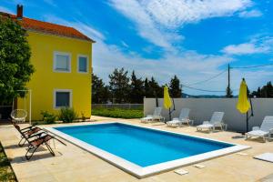 una piscina con sillas y una casa en Villa Kutija, en Sveti Filip i Jakov
