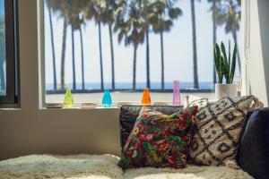 - un salon avec un canapé et une fenêtre agrémentée de palmiers dans l'établissement STAY OPEN Venice Beach, à Venice
