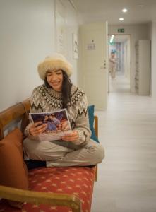 a woman sitting on a bench reading a book at Capsule Hotel Ibedcity in Rovaniemi