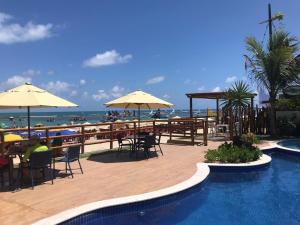 嘎林海斯港的住宿－PLAGE DU PORTO 204- Beira mar, centrinho turístico，海滩旁带桌子和遮阳伞的游泳池