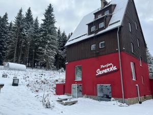 a red barn in a snowy field with trees at Severka in Háj