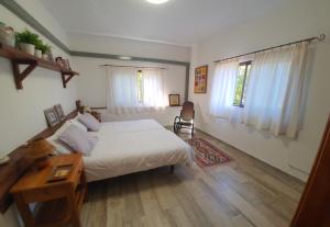 a bedroom with a bed and a desk and windows at Casa el Porte in Tegueste