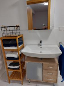 a bathroom with a sink and a shelf with towels at Ferienwohnung Juco in Heddesheim