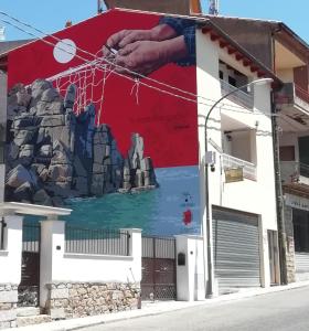 un grande murale sul lato di un edificio di B&B S'Apposentu ad Arbus