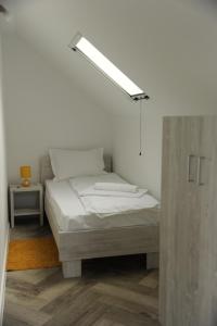 a bed in a white room with a light above it at Sobe_mis in Čačak