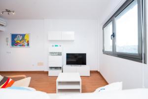 Una sala de estar con muebles blancos y una gran ventana. en Alojamiento en primera línea de playa en Arinaga, en Arinaga