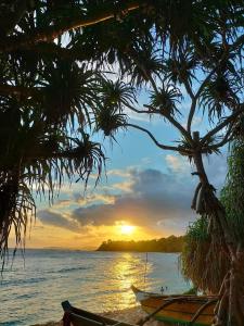 a boat sitting on the beach with a sunset at Kavidi Villa Home Stay in Tangalle