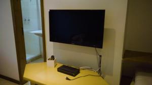 a flat screen tv on a wall with a table at Belíssima Casa com extensa área externa - piscina, sauna, churrasqueira e campo de futebol - com 5 suítes e a 500 metros da Rua das Pedras in Búzios