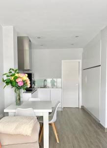 a white kitchen with a table and a vase of flowers at Luxury Attics Avenida Italia PARKING INCLUIDO in Huelva
