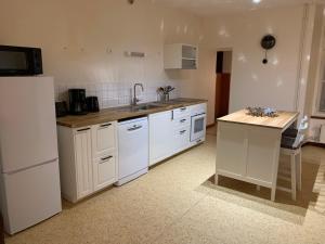 a kitchen with white cabinets and a sink and a refrigerator at Grand appartement tout confort en plein coeur d'Arbois in Arbois +9 photos