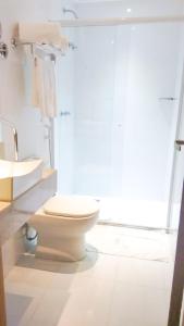 a white bathroom with a toilet and a sink at Mar Suítes Yguassú in Nova Iguaçu