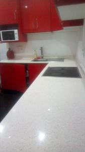 cocina con armarios rojos y encimera blanca en Jackies Guest House, en Durban