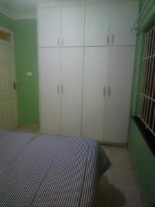 1 dormitorio con armarios blancos en una sala verde en Jackies Guest House, en Durban