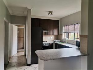 a kitchen with brown cabinets and a counter top at Centurion Cosy Apartment in Centurion