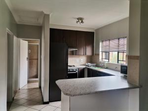 Una cocina con gabinetes marrones y una encimera. en Centurion Cosy Apartment, en Centurion