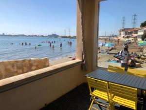 a view from a window of a beach with people in the water at La Maison de La Mer - RDC in Fos-sur-Mer