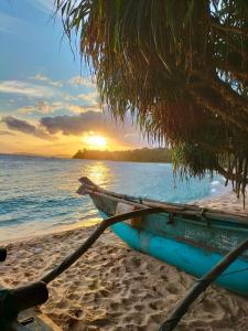 a blue boat sitting on a beach with the sunset at Kavidi Villa Home Stay in Tangalle