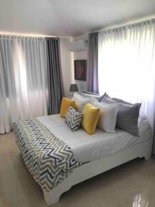 um quarto com uma cama com almofadas amarelas e brancas em Cozy 2 Bedrooms Apartment In Puerto Plata em San Felipe de Puerto Plata
