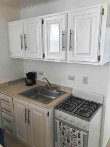 una cocina con armarios blancos y fregadero en Cozy 2 Bedrooms Apartment In Puerto Plata en San Felipe de Puerto Plata