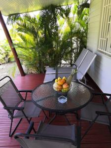 una mesa y sillas en un porche con un bol de fruta en DADI'S LITTLE PARADIS, en Sainte-Rose