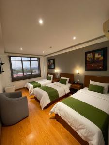 Habitación con 3 camas con sábanas verdes y blancas en Hotel Plaza Monte Carlo en Guayaquil