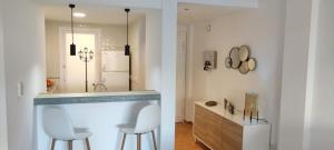 La salle de bains est pourvue de 2 chaises blanches et d'un comptoir avec lavabo. dans l'établissement Oasis Hoyo 12 - Oliva Nova playa MET&GOLF, à Oliva