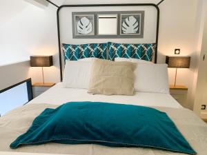 Un dormitorio con una cama con una manta azul. en Le Pétrel Noir - Appartement sur la plage des Roches Noires à Saint-Gilles-les-Bains en Saint-Gilles-les-Bains