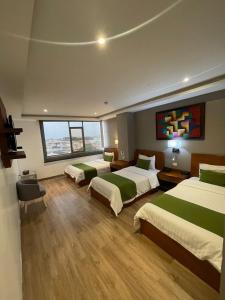 グアヤキルにあるHotel Plaza Monte Carloのベッド3台と大きな窓が備わるホテルルームです。