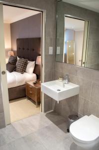 a bathroom with a sink and a bedroom with a bed at Dreamhouse at Blythswood Apartments Glasgow in Glasgow